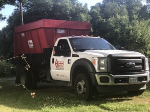 An AA Quick Disposal truck with a red dumpster on its bed, ready for junk removal in Kansas City, MO.