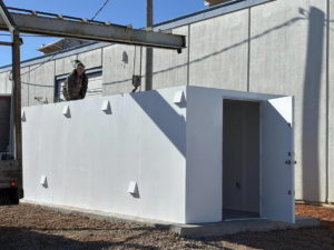 A worker on top of an above-ground storm shelter being installed on a concrete pad by Enid Storm Shelters in Enid, OK.