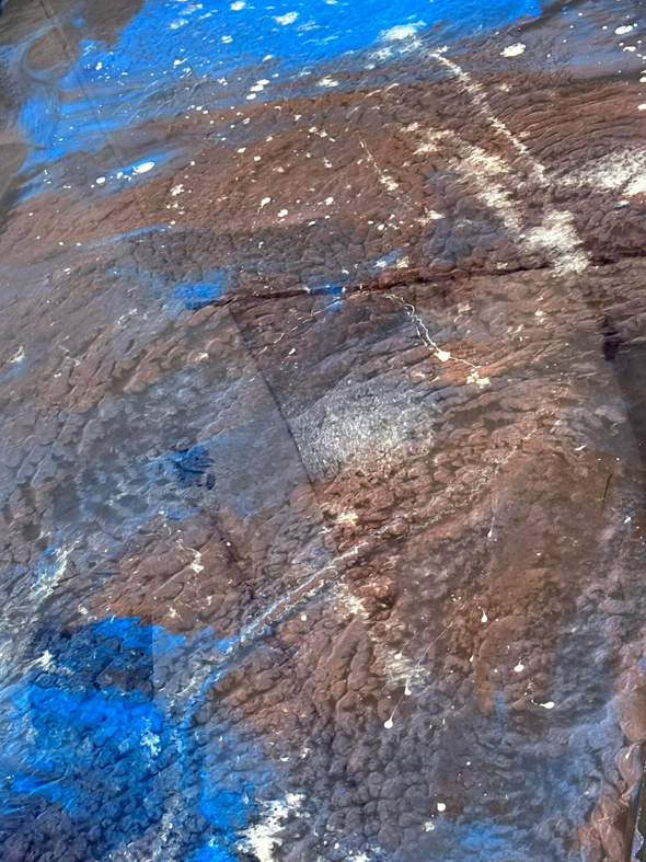 A close-up view of a decorative blue, brown, and white abstract epoxy floor design by Quality Painting of Raleigh in Raleigh, NC.