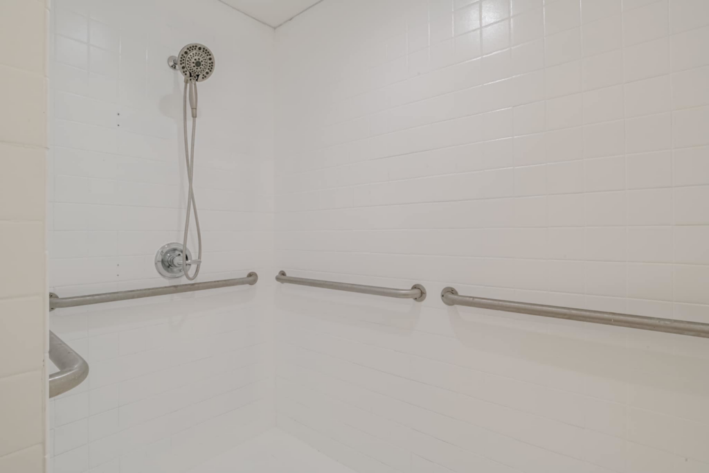 A newly installed accessible shower with grab bars and a modern shower head by SSS Solutions, LLC in Mobile, AL.