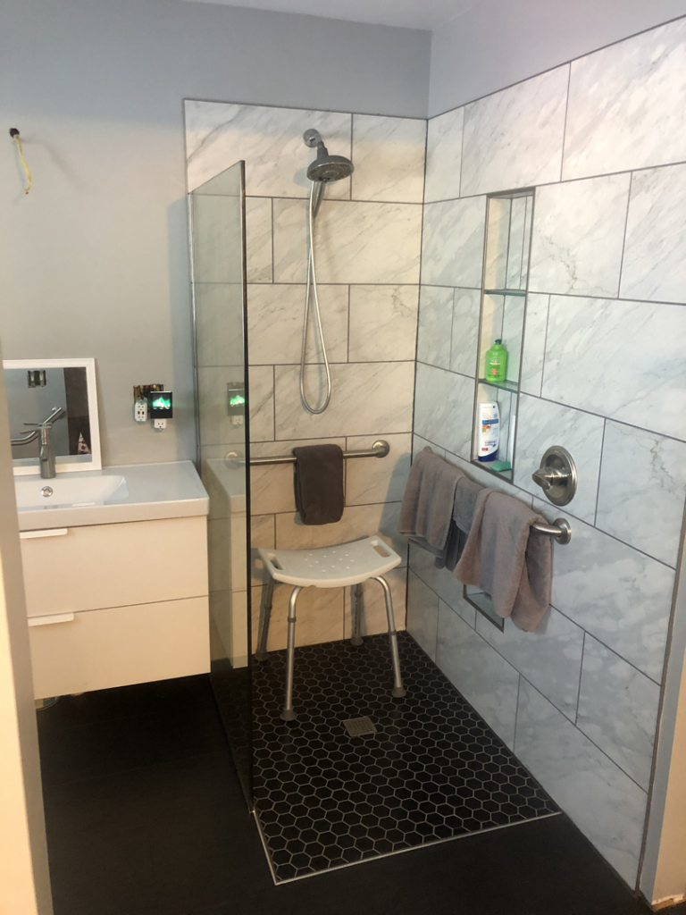 An accessible walk-in shower with grab bars and a bench installed by Elde Contracting in Saint Paul, MN.