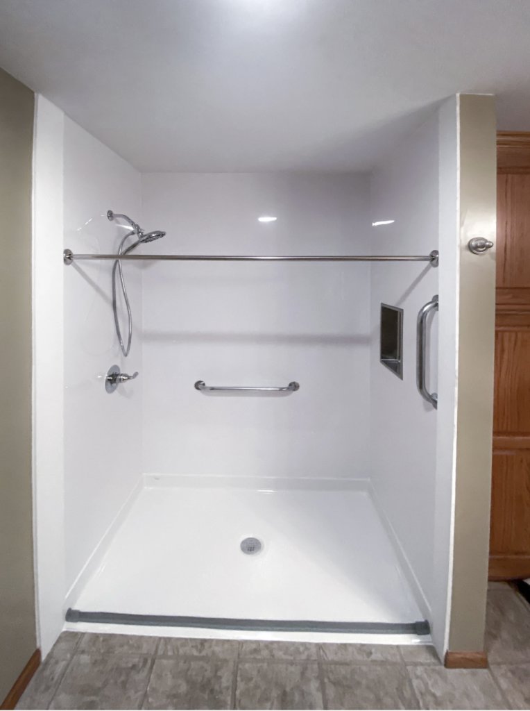 An accessible walk-in shower with grab bars installed by Thrive Homes, LLC in Olathe, KS.