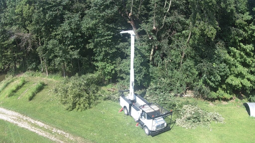An aerial view of a bucket truck and cut branches in a wooded area, indicating tree clearing by Crockett's Tree Service in Lafayette, IN.