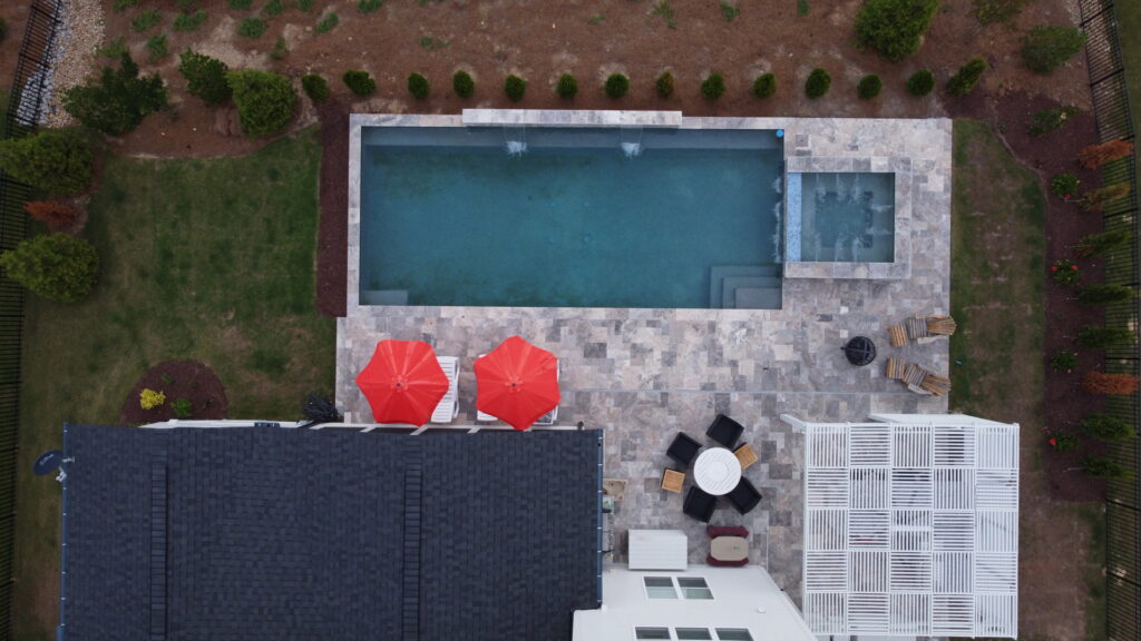 An aerial view of a modern pool, patio, and pergola installation by Extreme Pools Renovation in Raleigh, NC.