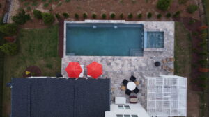 An aerial view of a modern pool, patio, and pergola installation by Extreme Pools Renovation in Raleigh, NC.