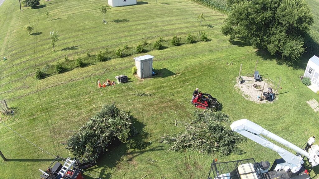 An aerial view of tree clearing with piles of branches, a skid steer, and a bucket truck by Crockett's Tree Service in Lafayette, IN.