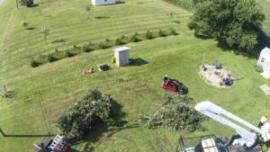 An aerial view of tree clearing with piles of branches, a skid steer, and a bucket truck by Crockett's Tree Service in Lafayette, IN.