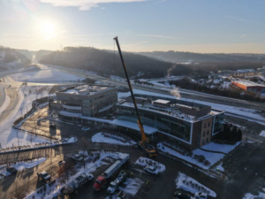 An aerial view of a building under construction with a large crane on a snowy day, showcasing a project by McKamish, Inc. in Pittsburgh, PA