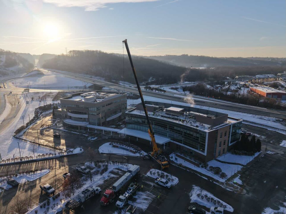 An aerial view of a building under construction with a large crane on a snowy day, showcasing a project by McKamish, Inc. in Pittsburgh, PA