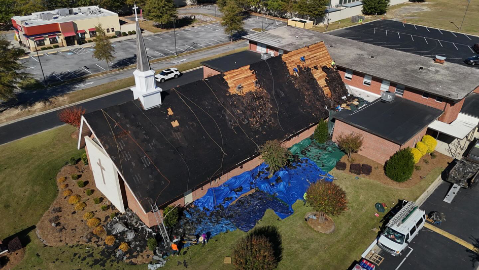 An aerial view of a church roof replacement project in progress by First Choice Roofing in Cary, NC.