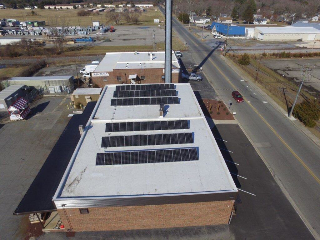 An aerial view of a commercial building with solar panels installed on its roof by Bayside Exteriors in Lewes, DE.