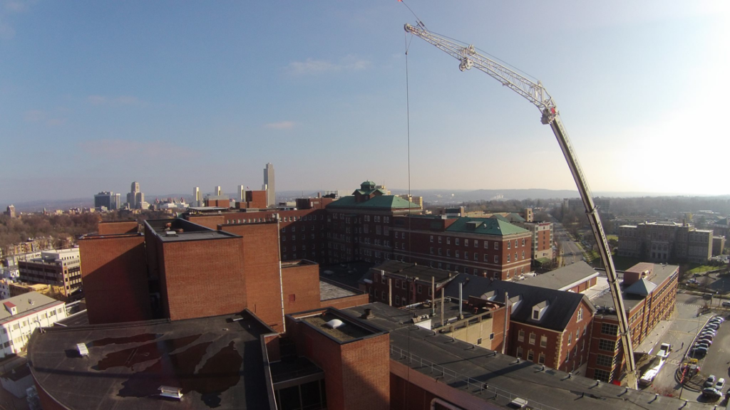 An aerial view of a large crane on a construction site in a city, demonstrating heavy lifting services by Mullins Rigging in Green Island, NY