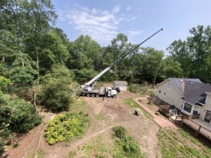 An aerial view of a large crane truck set up in a residential backyard for tree removal services by Infinity Tree Service in Augusta, GA.