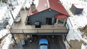 An aerial view of a newly built elevated deck on a house in a snowy landscape by AG - Deck Masters in Arvada, CO.
