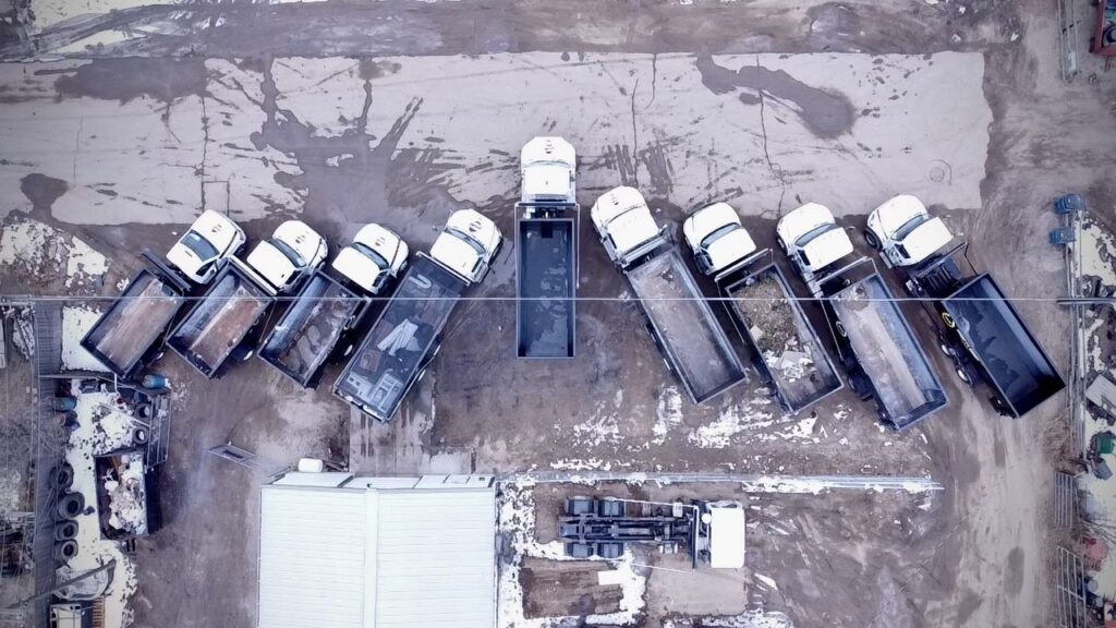 An aerial view of the Humpty Dump Roll-Offs & Dumpsters fleet of dump trucks and dumpsters parked in a lot in Commerce City, CO.