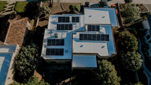 Aerial view of a residential house with a white flat roof and solar panels by Campos & Son Roofing and Construction in El Paso, TX