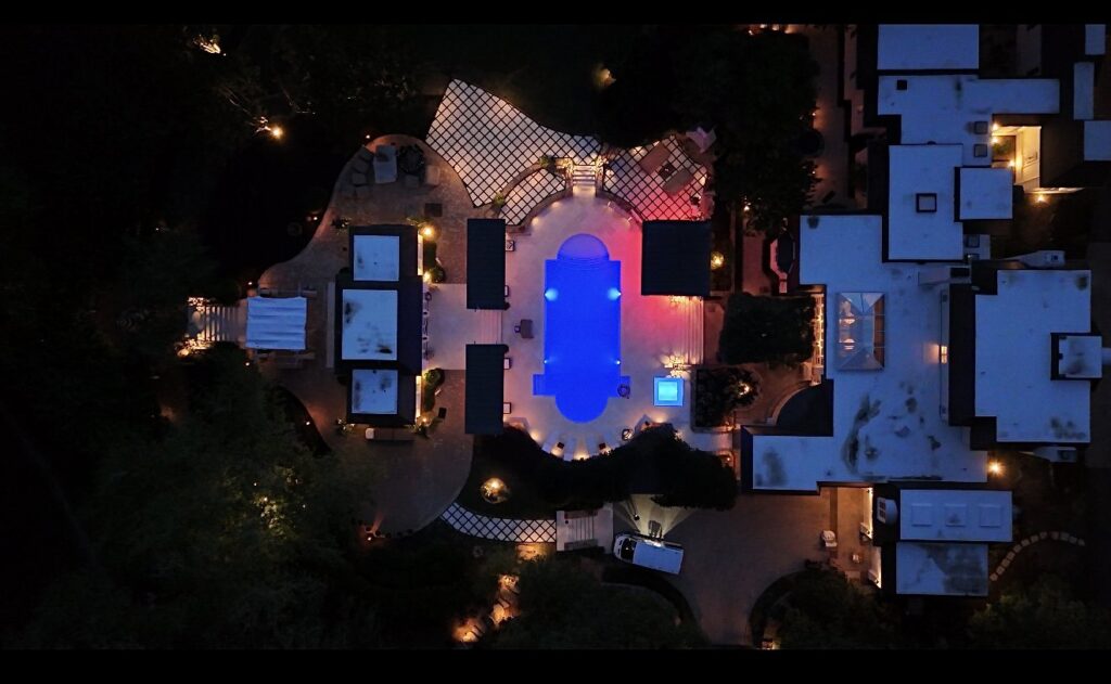 An aerial view of a luxurious backyard poolscape with extensive lighting, designed and built by Picasso Poolscapes in Johns Creek, GA.