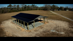An aerial view of a large metal barn or carport under construction with a concrete slab by Southern Style Barns & Buildings LLC in Lake Charles, LA.