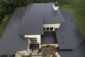 An aerial view of a modern house featuring a newly installed dark metal roof, showcasing work by APEX Roofing in Georgetown, TX.