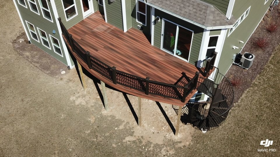 An aerial view of a newly constructed deck with a black spiral staircase by Screwheads Decking And Supply Store in Racine, WI