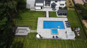 An aerial view of a newly installed pool, hot tub, patio, and fire pit by MVP Pools in Woodbridge, NJ