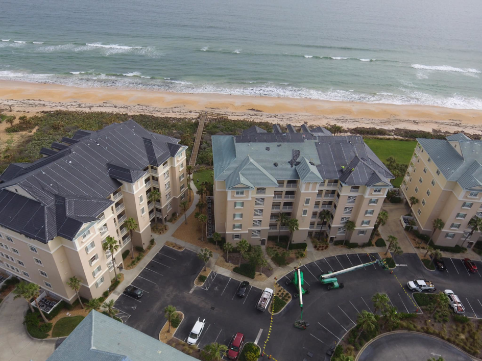Aerial view of beachfront buildings with newly installed roofs, showcasing work by CAT 5 Contracting in Jacksonville, FL