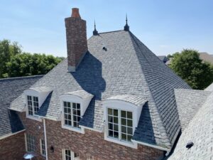 An aerial view of a large brick home with a newly installed grey shingle roof by First Contracting Group in Rockford, IL.