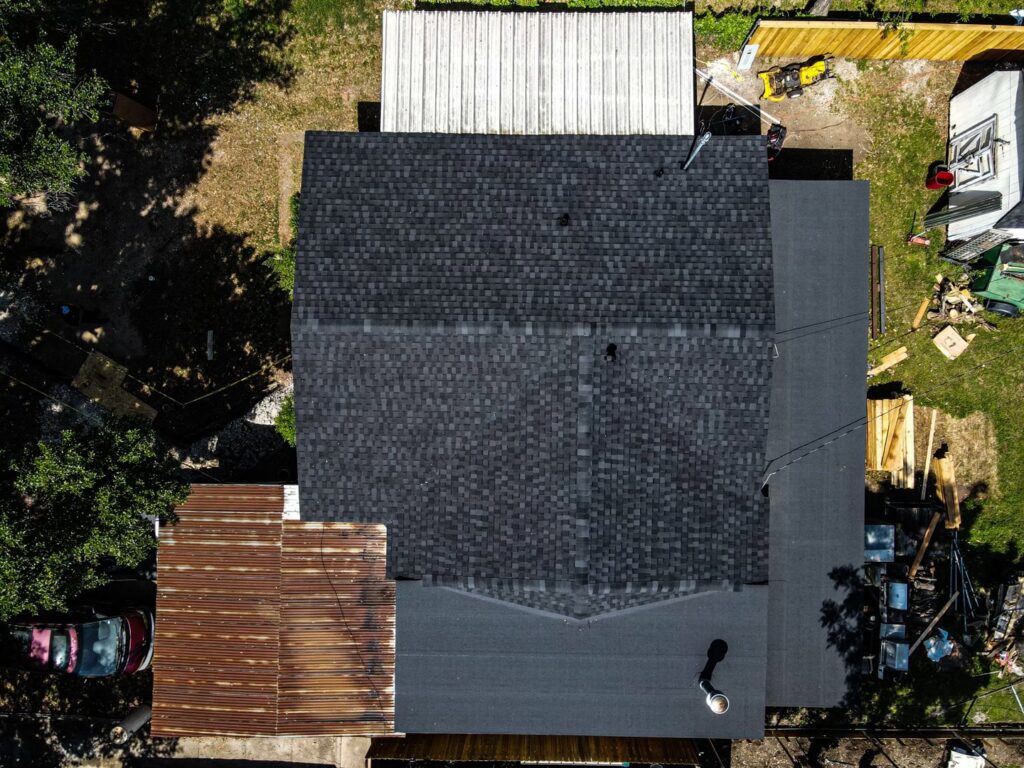An aerial view of a residential property with a newly installed shingle roof by Riker Home Services in Plano, TX