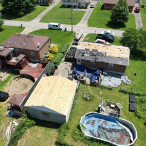 An aerial view of a house with roof replacement in progress and a new garage roof by GOAT Services, LLC in Louisville, KY.