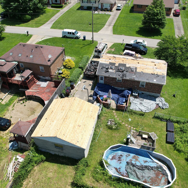 An aerial view of a house with roof replacement in progress and a new garage roof by GOAT Services, LLC in Louisville, KY.