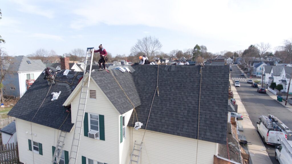 An aerial view of a roofing crew installing new shingles on a residential roof by Joe's Roofing in Strongsville, OH.