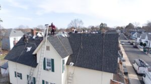 An aerial view of a roofing crew installing new shingles on a residential roof by Joe's Roofing in Strongsville, OH.