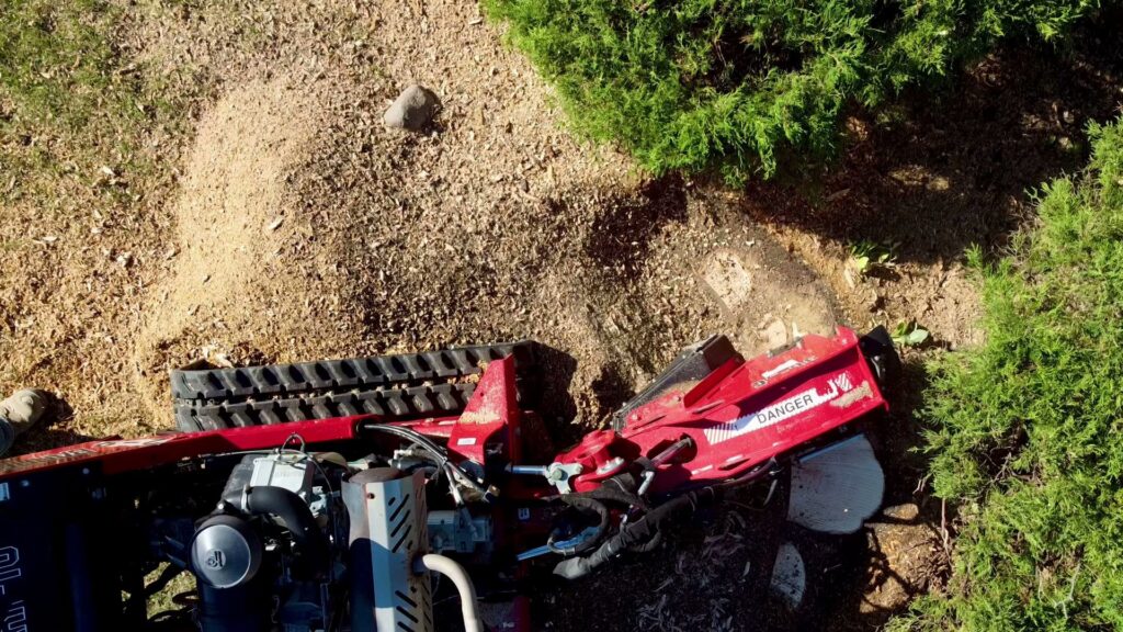 An aerial view of a stump grinder in action, removing a tree stump for Snyder's Tree Service LLC in Fort Wayne, IN.