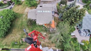 An aerial view of a tree removal site with a spider lift and residential property by Mountain Tree Company in Missoula, MT.