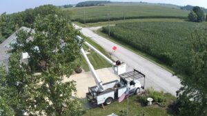 An aerial view of a worker in a bucket truck performing tree trimming near a residential home for Crockett's Tree Service in Lafayette, IN.