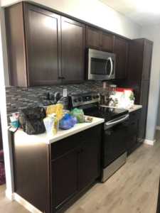 Completed kitchen remodel with new dark cabinets, backsplash, and stainless steel appliances by All in One Remodeling Services LLC in East Sandwich, MA