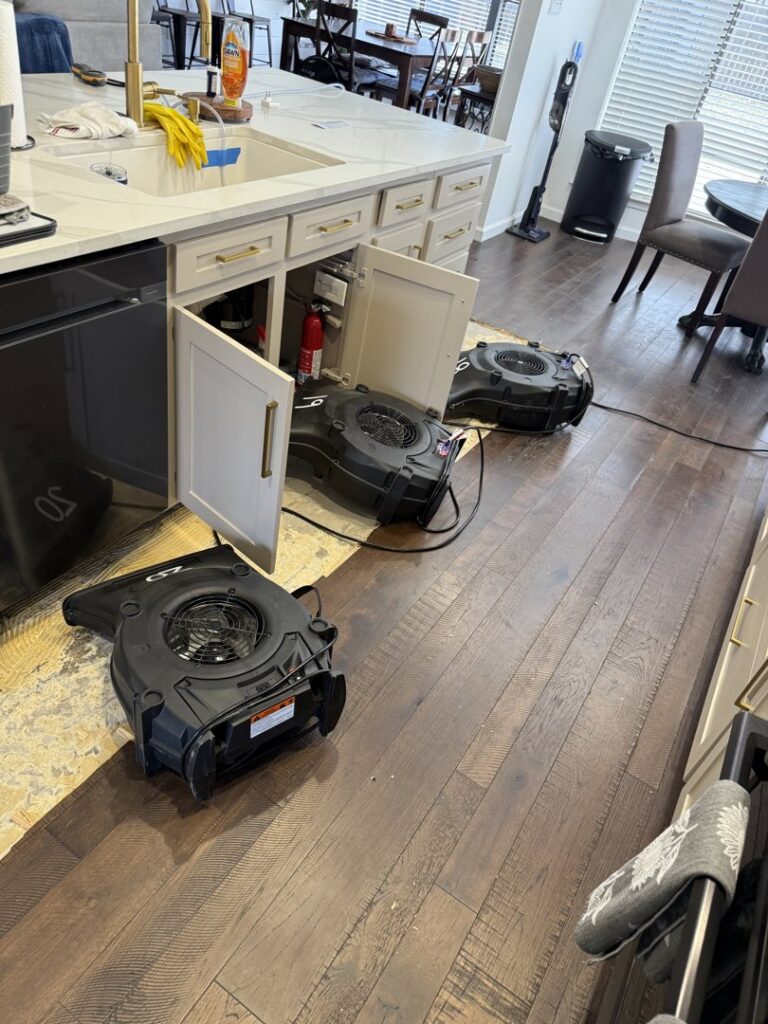 Air movers drying under kitchen cabinets for water damage restoration by Coyote Restoration in North Richland Hills, TX.