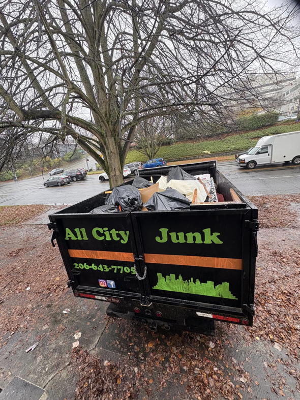 All City Junk Removal branded truck, loaded with debris and trash bags, parked on a street after a junk removal service in Kent, WA.