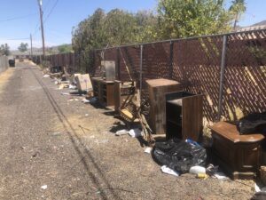 An alleyway cluttered with discarded furniture and trash bags, ready for Skunky's Junk Removal in Tempe, AZ.