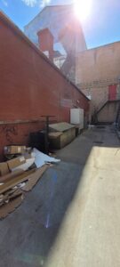 An alleyway filled with debris, cardboard, and old appliances, ready for removal by Clean Sweep Junk Removal in Augusta, ME.
