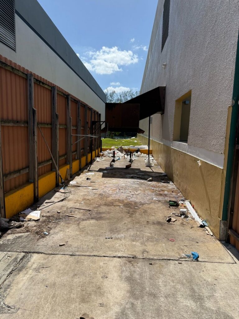 An outdoor alleyway with scattered trash and debris, indicating a cleanup job for Junk Be Gone in Miami, FL.