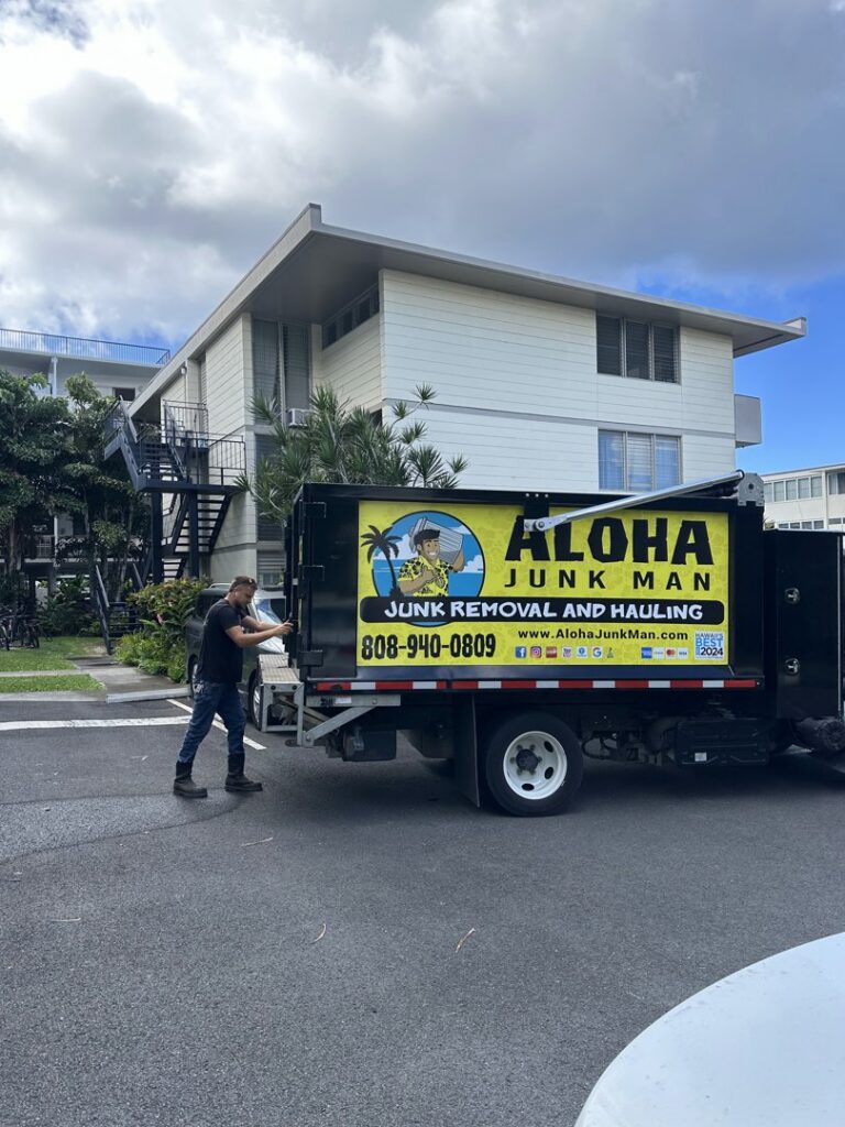An Aloha Junk Man truck and a team member at a residential or commercial junk removal job site in Kailua, HI.