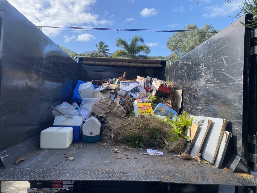 An Aloha Junk Man truck loaded with yard waste, coolers, and various junk items after a cleanout service in Kailua, HI.