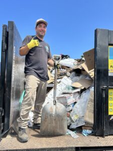 An Aloha Junk Man worker standing in a junk removal truck filled with various items and debris in Kailua, HI.