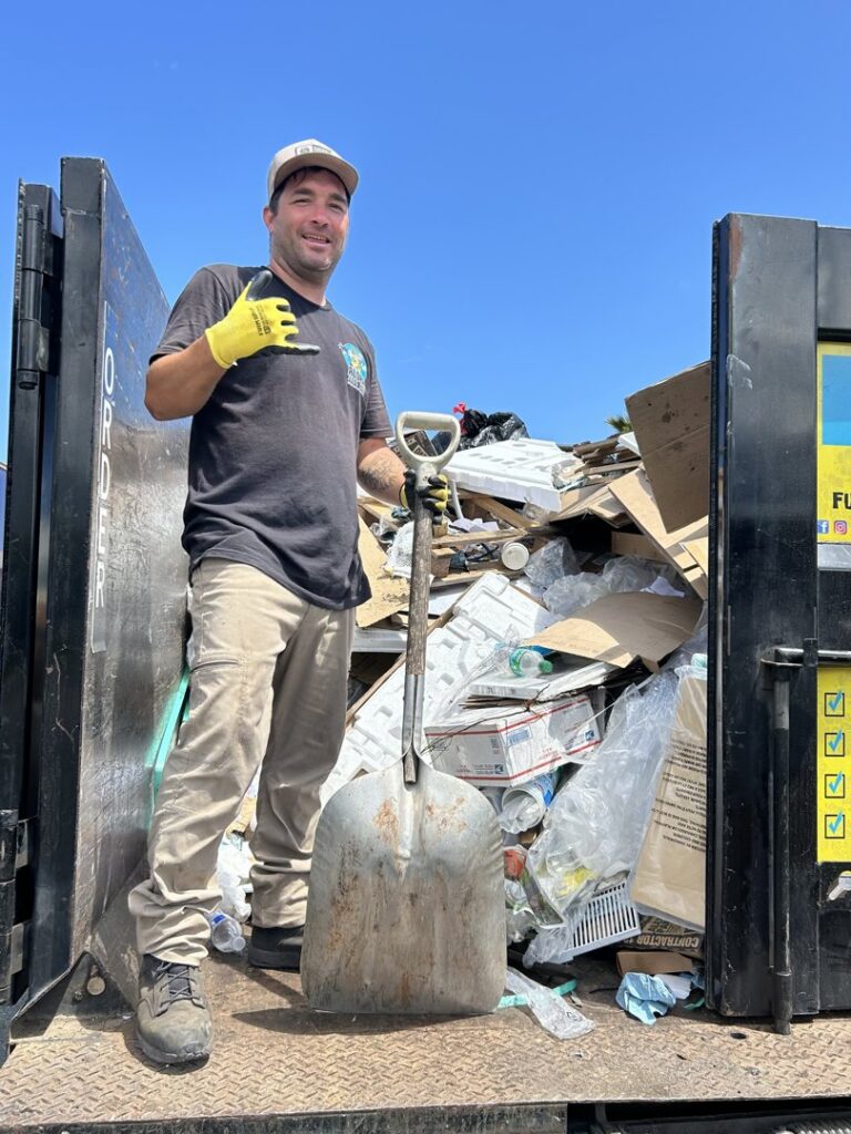 An Aloha Junk Man worker standing in a junk removal truck filled with various items and debris in Kailua, HI.