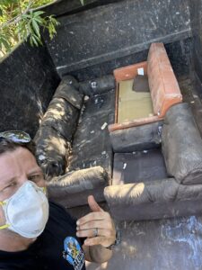 An Aloha Junk Man worker giving a thumbs up next to a truck filled with old couches and furniture after a removal job in Kailua, HI.
