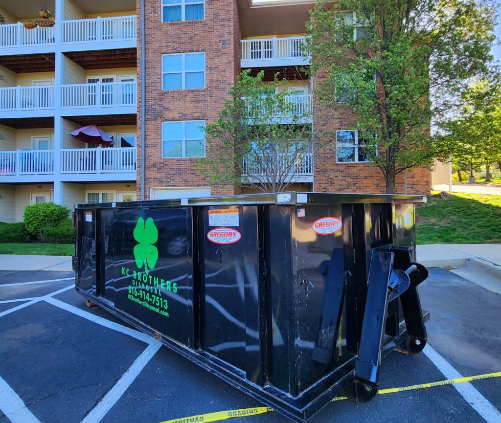 A KC Brothers Disposal dumpster parked in the lot of an apartment complex for waste management in Kansas City, MO.