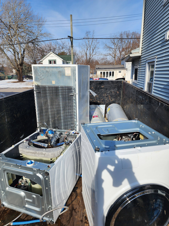 A trailer loaded with large appliances like a refrigerator and washing machines for removal by Curtis Rose Companies LLC in Janesville, WI.