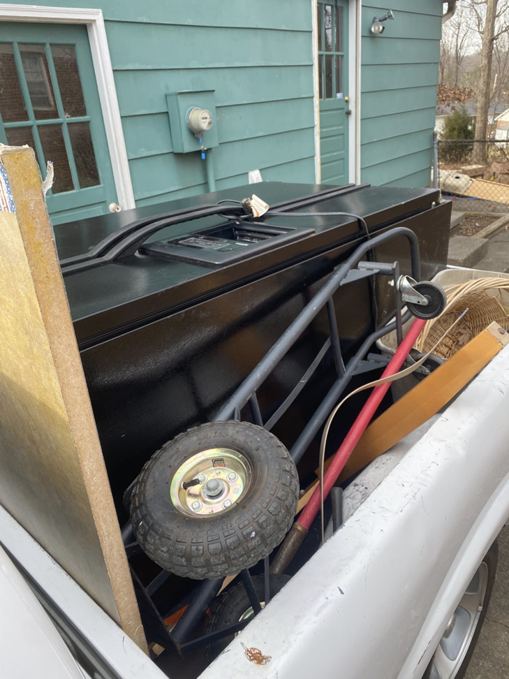 A truck bed loaded with a large black freezer and other junk for removal by Junk Crushers in Roseville, CA.