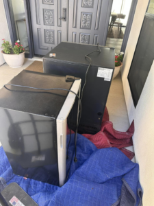 Mini-fridges and coolers placed on moving blankets, ready for appliance removal by HD Junk Removal in Gilbert, AZ